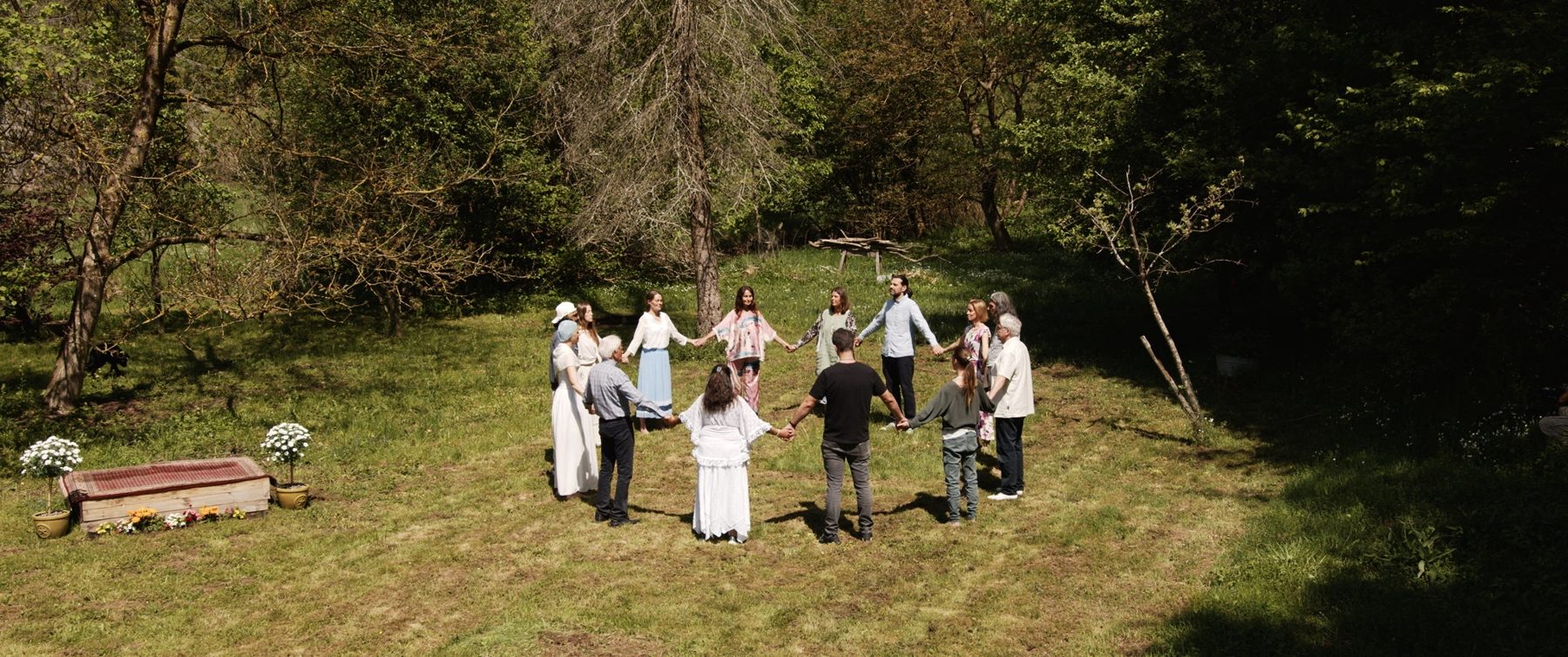 Menschen stehen auf einer Wiese im Kreis und halten sich an den Händen