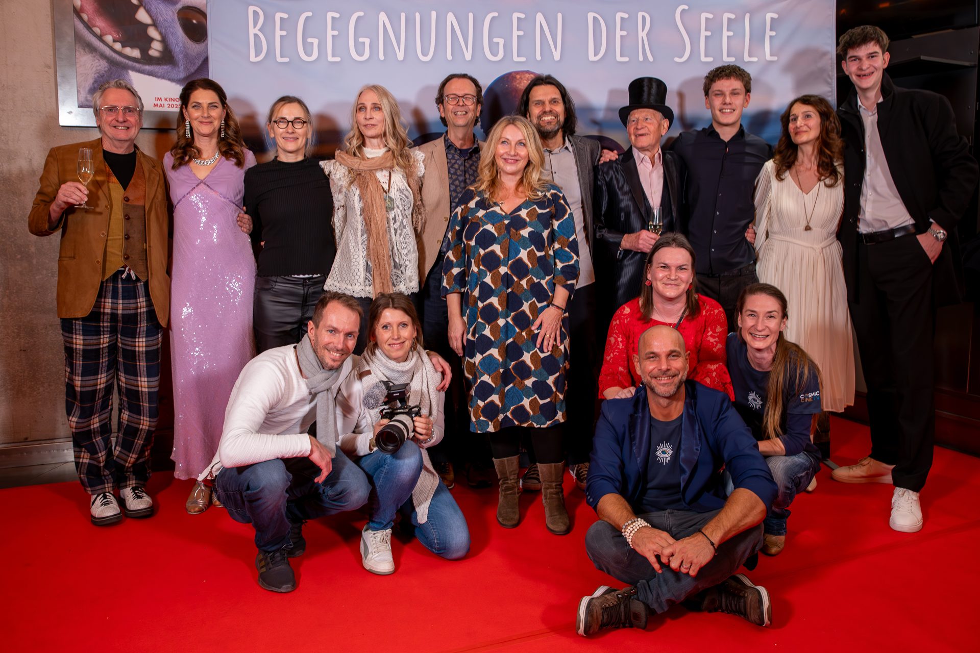 Gruppenbild des Teams und der Mitwirkenden auf dem roten Teppich vor dem Plakat von Begegnungen der Seele